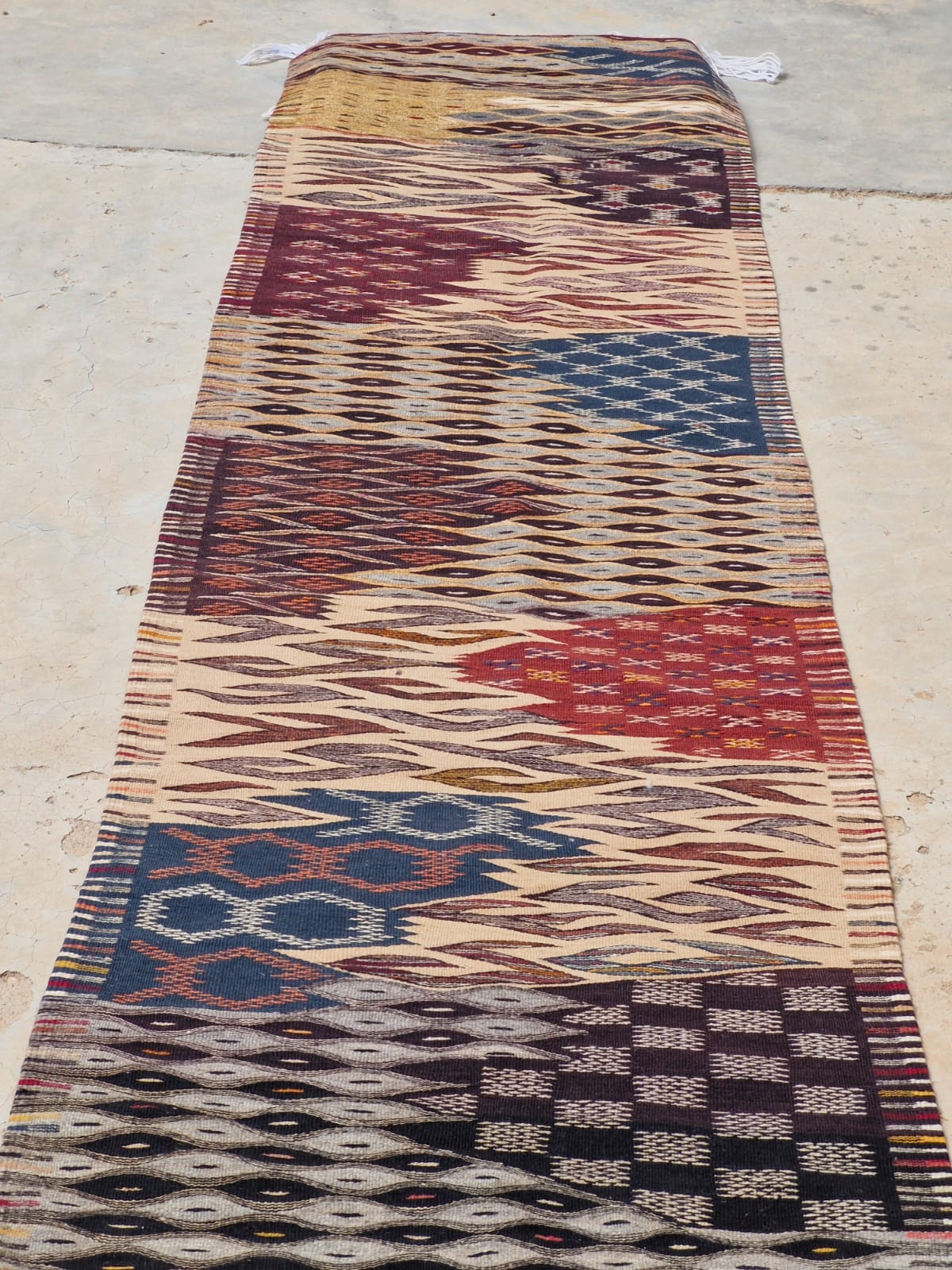 A long rectangular area rug with a multicolor geometric and tribal pattern, handmade Moroccan Berber rug from Taznakht, bohemian living room